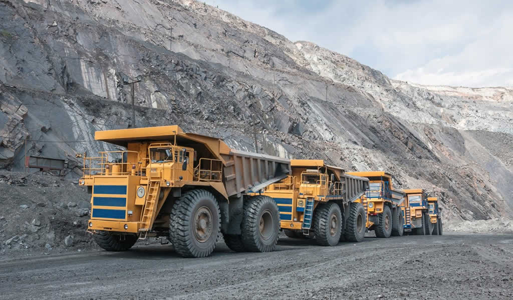 Flota de camiones mineros de gran tonelaje en una mina a cielo abierto, un entorno donde los polímeros de alta resistencia son esenciales.