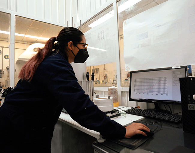 Ingeniera de Taza Polymer analizando datos de pruebas de polímeros en un laboratorio.