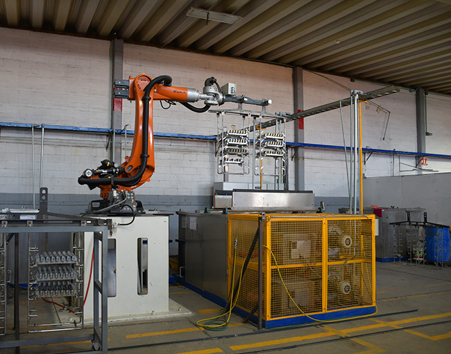 Un brazo robótico de la marca KUKA y una línea de montaje en un taller de fabricación industrial, mostrando el uso de tecnología avanzada en el proceso de producción.