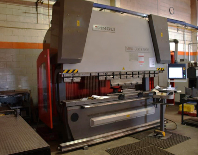 Una máquina dobladora de metal (press brake) de la marca YANGLI en un entorno de taller de fabricación industrial.
