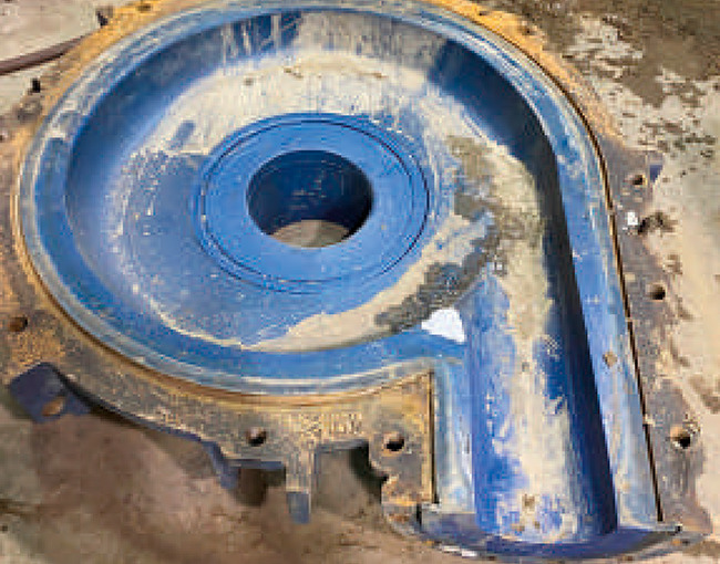 Carcasa de bomba o voluta de gran tamaño, recubierta de polímero azul, mostrando desgaste.