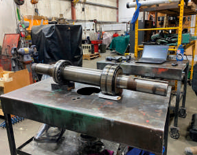 Eje industrial con rodamientos sobre una mesa de trabajo en el taller de TAZA, listo para ser revisado y reparado.