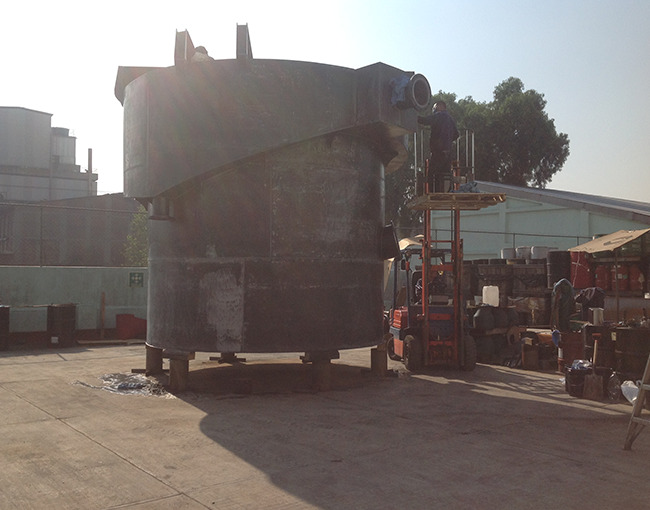 Trabajadores de TAZA revisando y preparando un tanque de gran tamaño antes del acabado final. Se observa un montacargas como andamio.