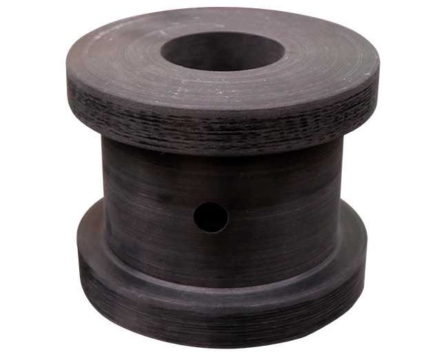 Una polea o buje industrial de poliuretano de color negro o gris oscuro. La pieza tiene un diseño en forma de carrete o doble disco con un orificio central grande y un orificio pasante más pequeño en el cuerpo cilíndrico. La superficie de la pieza muestra las marcas circulares del maquinado.