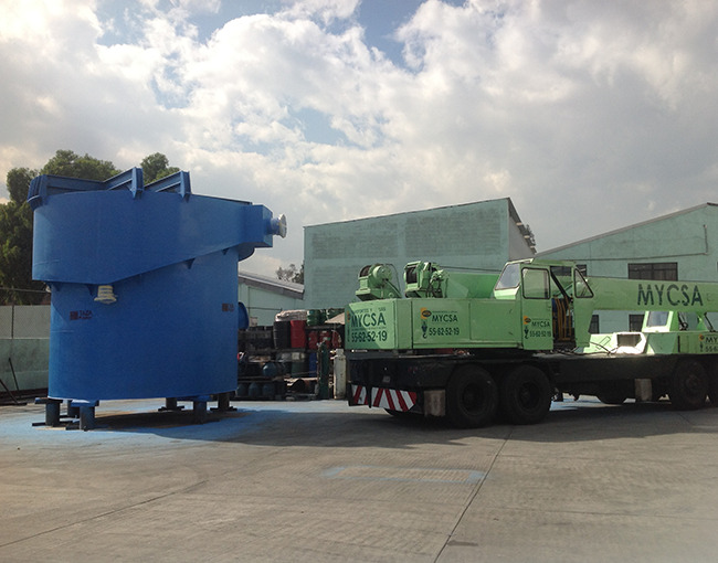 Grúa industrial de MYCSA levantando una tolva de acero de gran tamaño en la planta de TAZA.