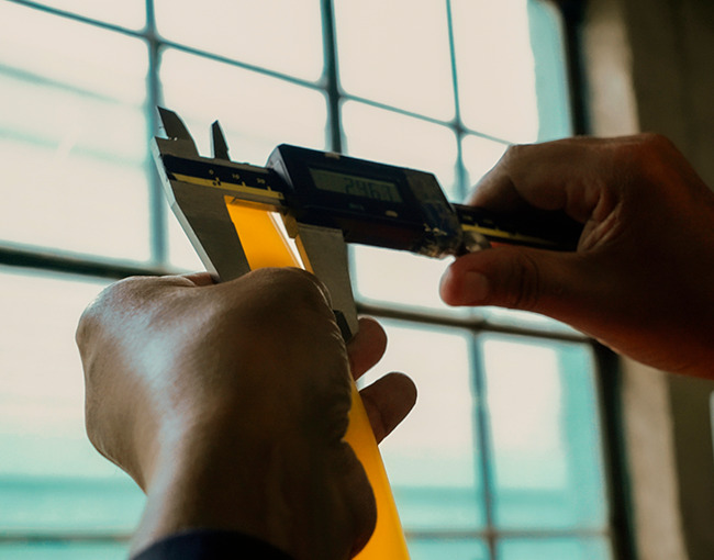 Ingeniero midiendo el diámetro de un polímero con un vernier digital de alta precisión.