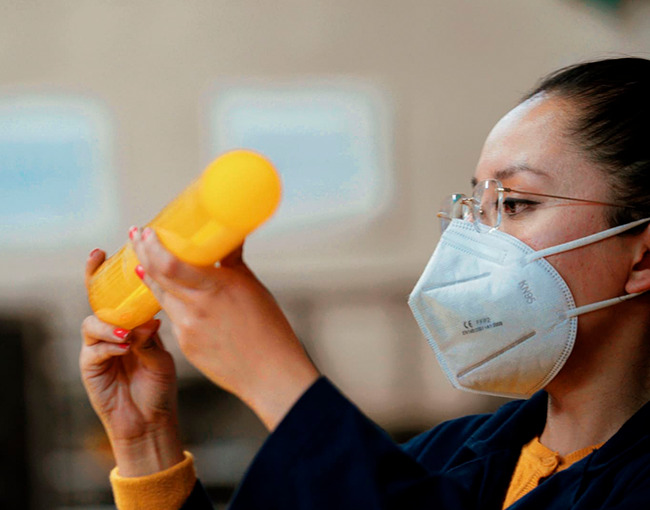 Ingeniera de Taza Polymer realizando inspección visual de una pieza de polímero transparente.