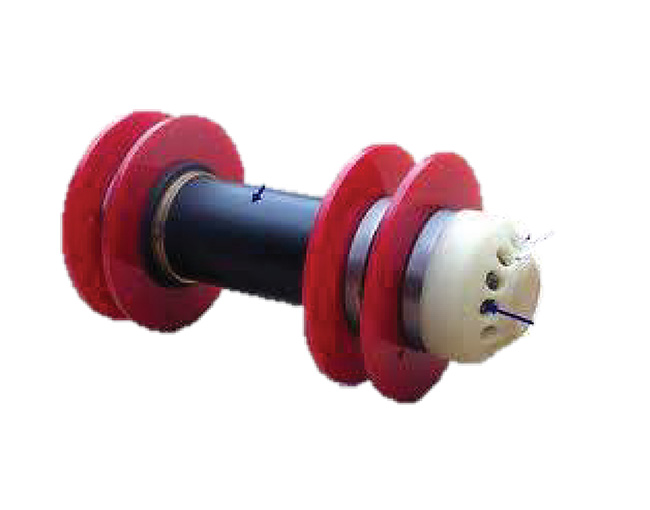 Componente industrial con un eje central de color negro, discos circulares de color rojo y una pieza de polímero blanca en el extremo.